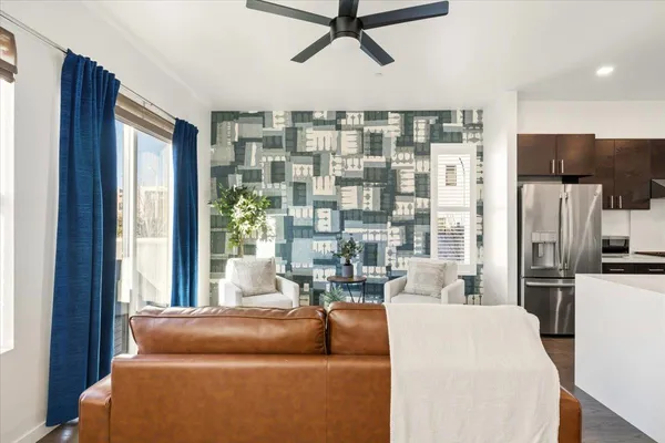 a living room with furniture a large window and stainless steel appliances