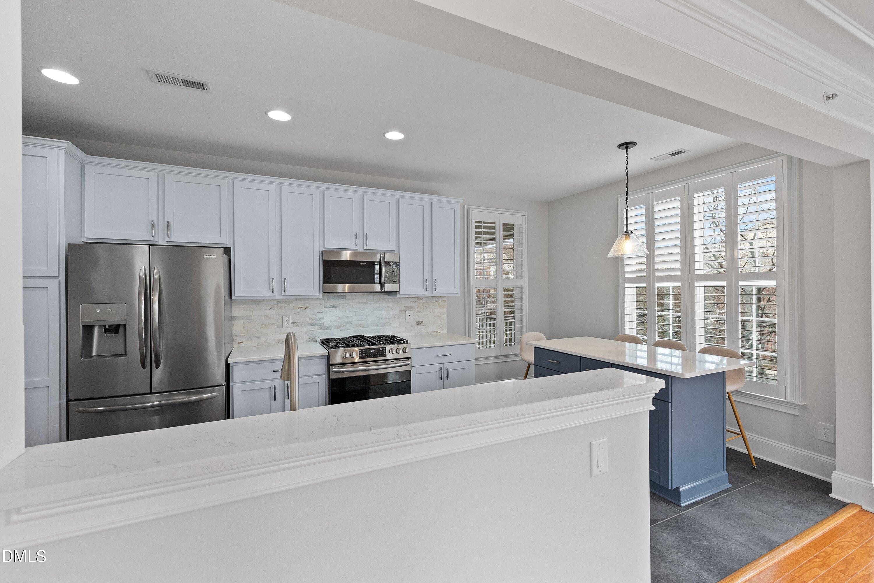 9211 Calabria Drive, Unit 205 Raleigh, NC 27617 - Photo 18 of 55 a kitchen with stainless steel appliances kitchen island granite countertop a refrigerator stove microwave and sink