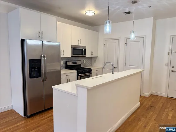 a kitchen with kitchen island a sink stainless steel appliances and wooden floor