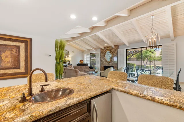 a kitchen with stainless steel appliances a sink a stove a refrigerator cabinets and dining table