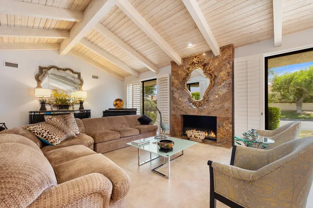 a living room with furniture a fireplace and a large window