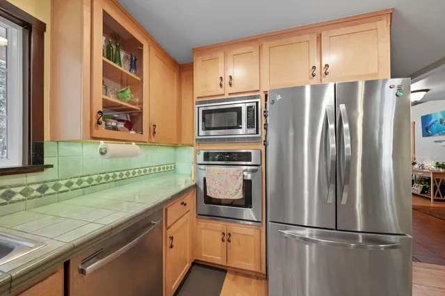 a kitchen with stainless steel appliances kitchen island granite countertop a table chairs sink and cabinets