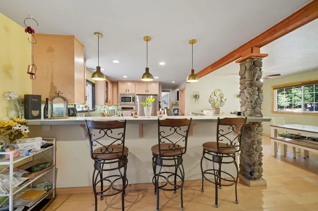 a kitchen with a stove a chandelier and a view of living room