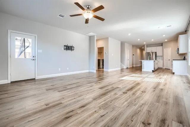 a view of a kitchen with wooden floor and a ceiling fan