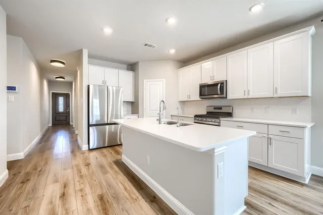 a kitchen with a sink a counter top space stainless steel appliances and cabinets