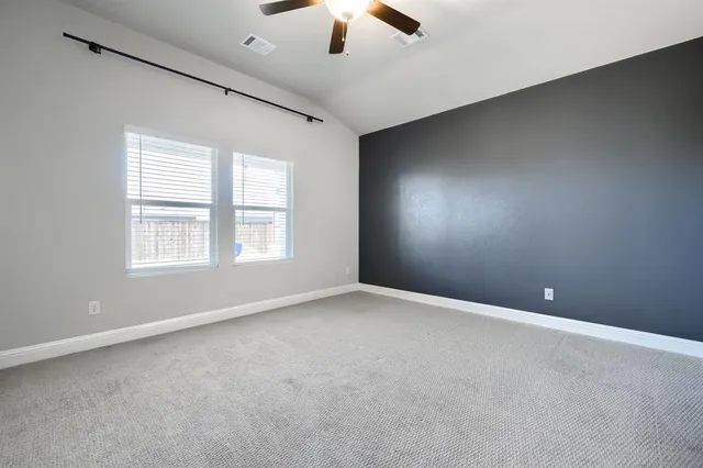 an empty room with chandelier fan and windows