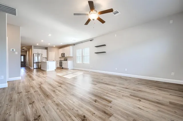 a view of empty room with wooden floor and fan