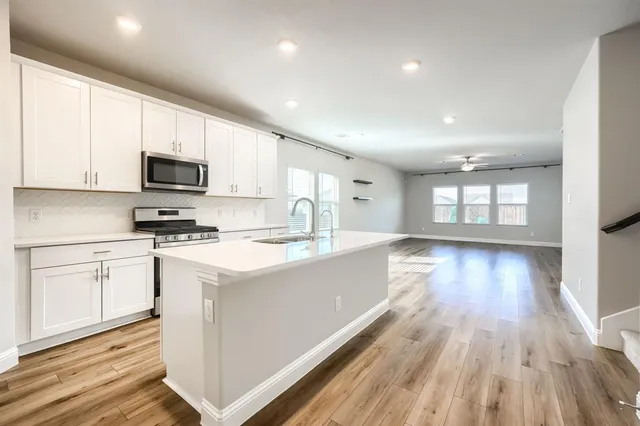 a kitchen with granite countertop a stove top oven a sink dishwasher and a microwave with wooden floor