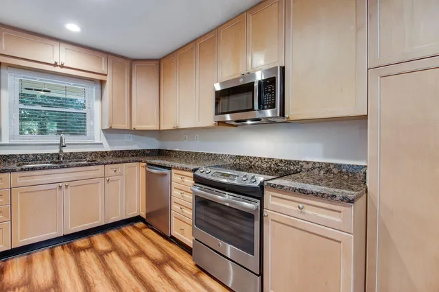 a kitchen with granite countertop white cabinets stainless steel appliances and a sink