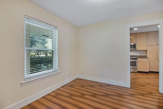 a view of an empty room with a window and wooden floor