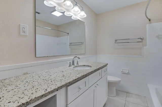 a bathroom with a granite countertop sink a toilet and a mirror