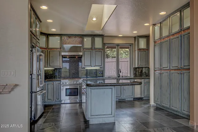 a kitchen with stainless steel appliances granite countertop a sink and a refrigerator