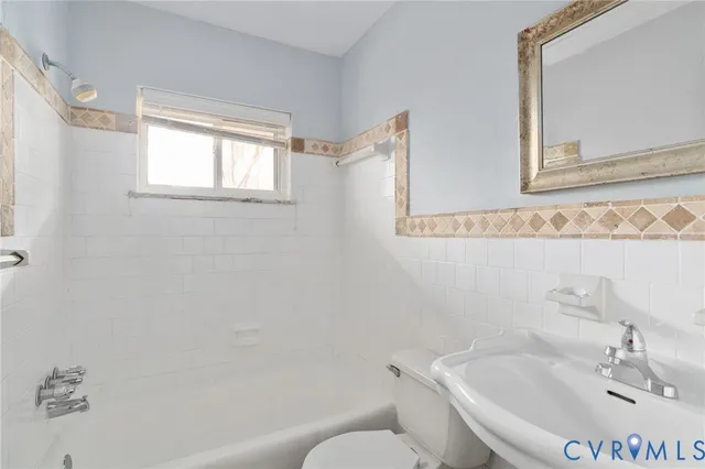 a white bath tub sitting next to a white sink and a mirror