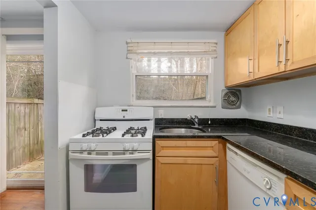 a kitchen with granite countertop cabinets sink and white appliances