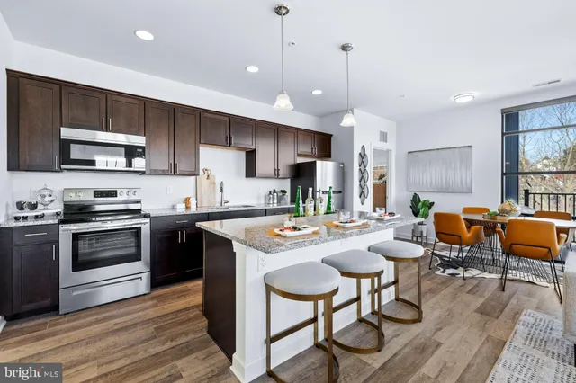 a kitchen with stainless steel appliances granite countertop a stove a sink a microwave a center island and furniture