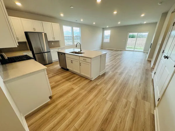 a open kitchen with stainless steel appliances granite countertop a refrigerator a sink dishwasher and a stove with wooden floor