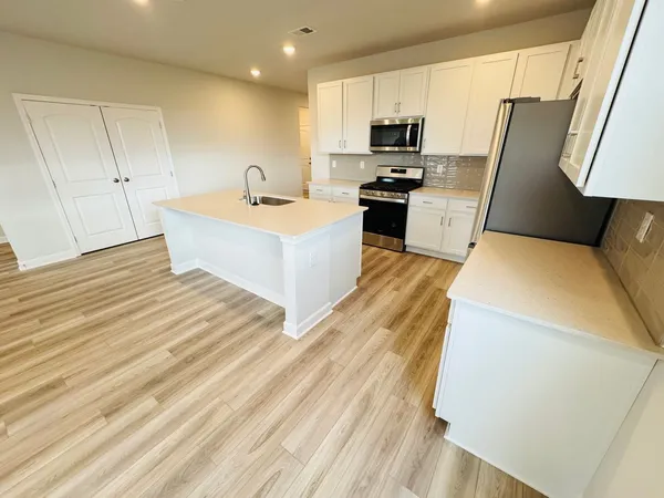 a kitchen with stainless steel appliances a microwave a sink a stove a refrigerator and cabinets