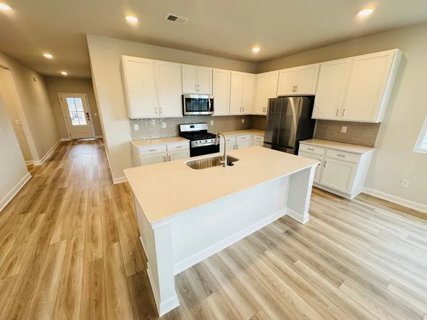 a kitchen with a sink a wooden floor and stainless steel appliances