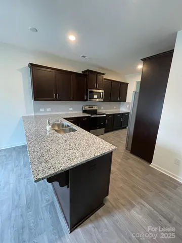 a kitchen with stainless steel appliances kitchen island granite countertop wooden floor sink and stove