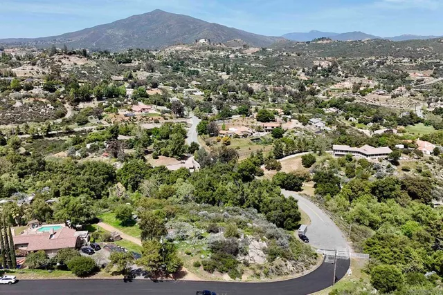 an aerial view of a houses with a street and green space