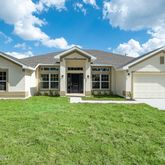 a view of a house with a big yard and large trees