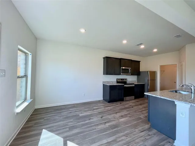a living room with stainless steel appliances kitchen island granite countertop a refrigerator stove and sink