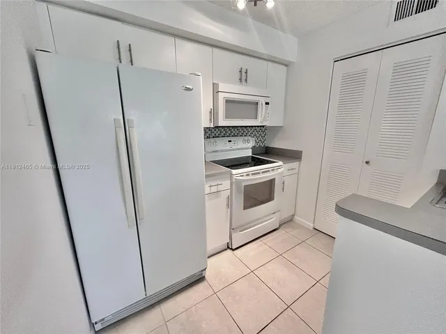 a white refrigerator freezer and a stove sitting inside of a kitchen