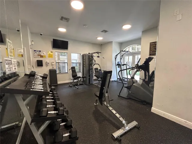 a room with gym equipment and wooden floor