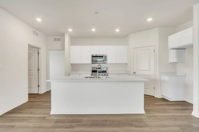 a large kitchen with stainless steel appliances granite countertop a large counter top and a wooden floors