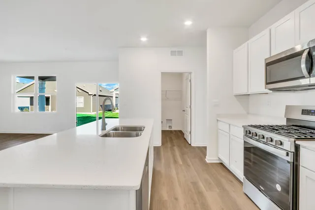 a kitchen with stainless steel appliances a stove a microwave a sink and cabinets