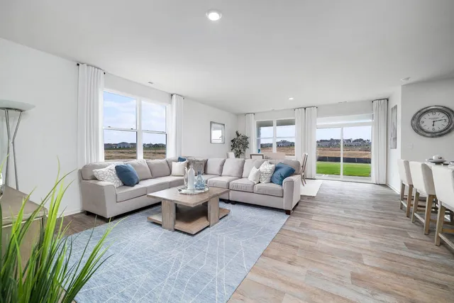 a kitchen with kitchen island granite countertop a dining table chairs refrigerator and cabinets