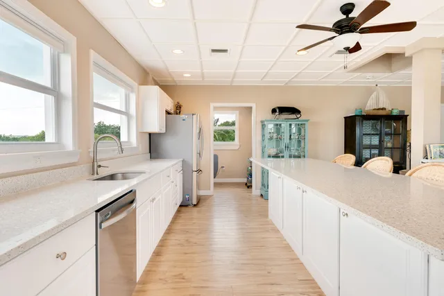a kitchen with stainless steel appliances white cabinets a sink a stove a microwave and wooden floors