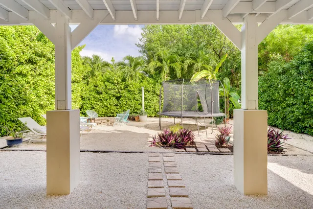 a backyard of a house with table and chairs and potted plants