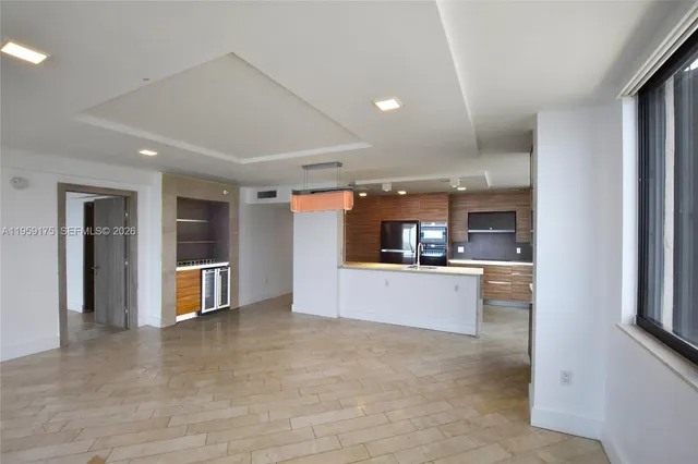 a view of a living room kitchen with stainless steel appliances wooden floor and a large window