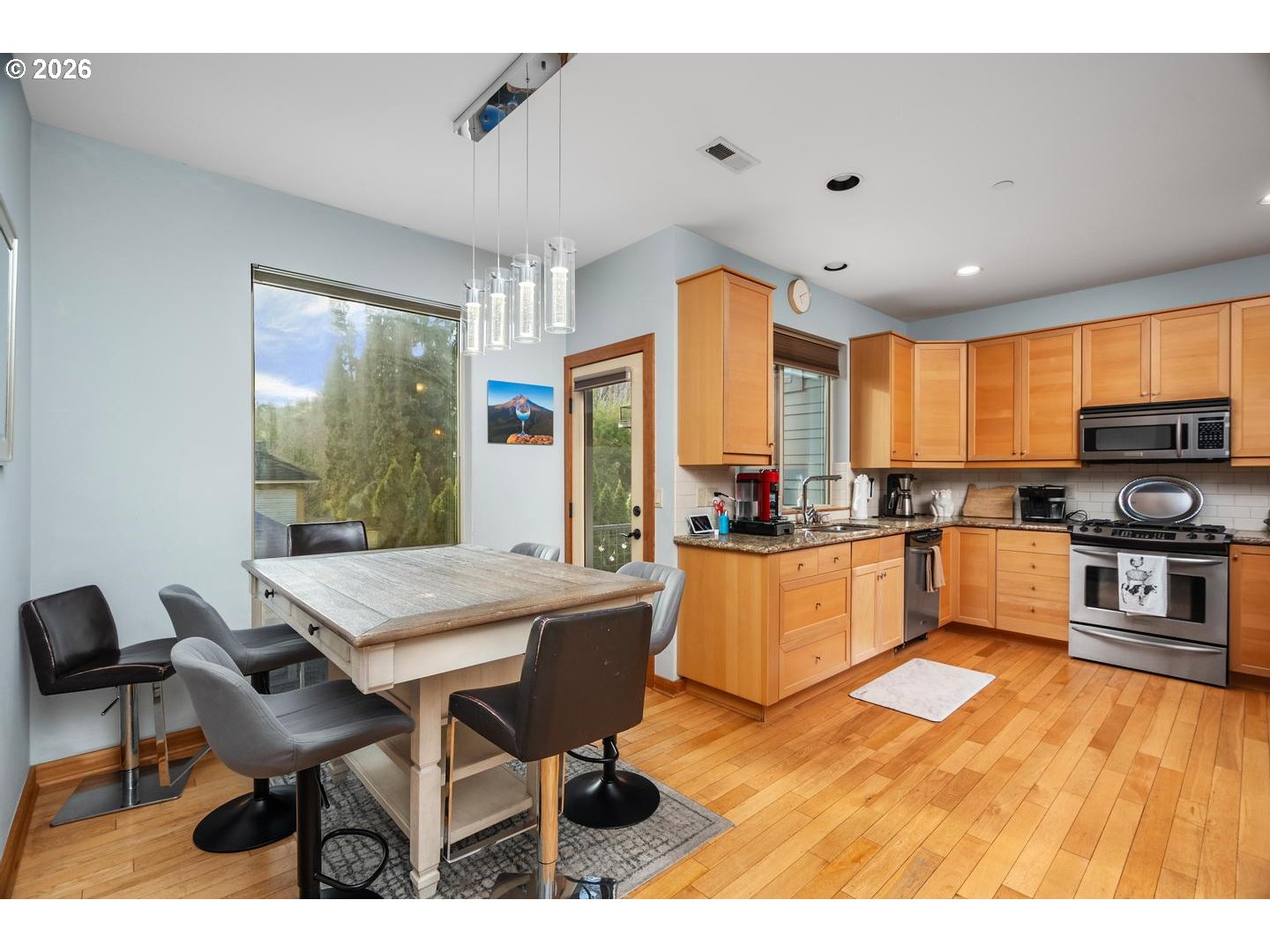 5047 Southwest View Point Terrace, Unit C Portland, OR 97239 - Photo 5 of 38 a kitchen with stainless steel appliances kitchen island granite countertop a table chairs sink and cabinets