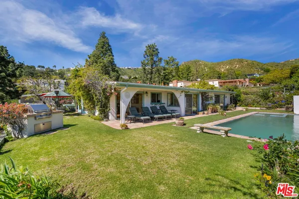 a view of swimming pool with a table and chairs under an umbrella
