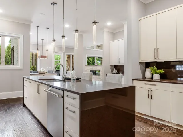 a kitchen with stainless steel appliances granite countertop a sink a stove and white cabinets with wooden floor