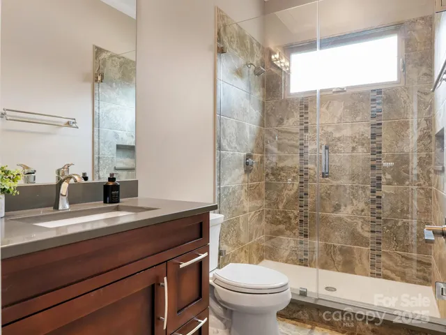 a bathroom with a sink a toilet a mirror and shower