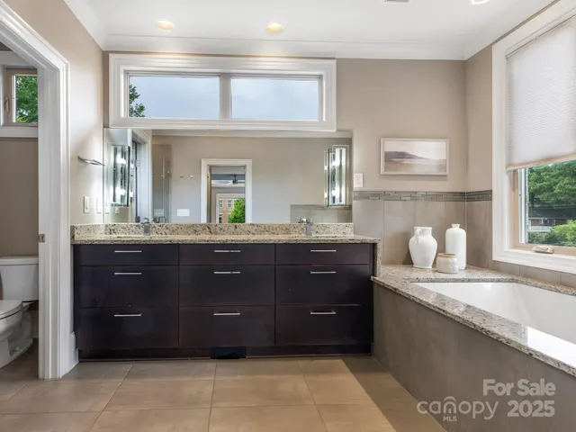 a bathroom with a granite countertop vanity a sink a mirror and a bathtub