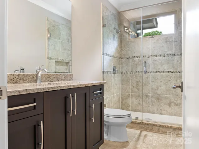 a bathroom with a granite countertop shower a sink and a toilet