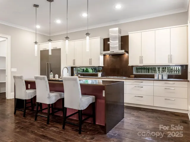 a kitchen with stainless steel appliances kitchen island granite countertop a table chairs and a refrigerator