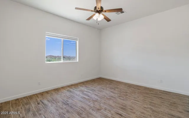 an empty room with wooden floor and ceiling fan