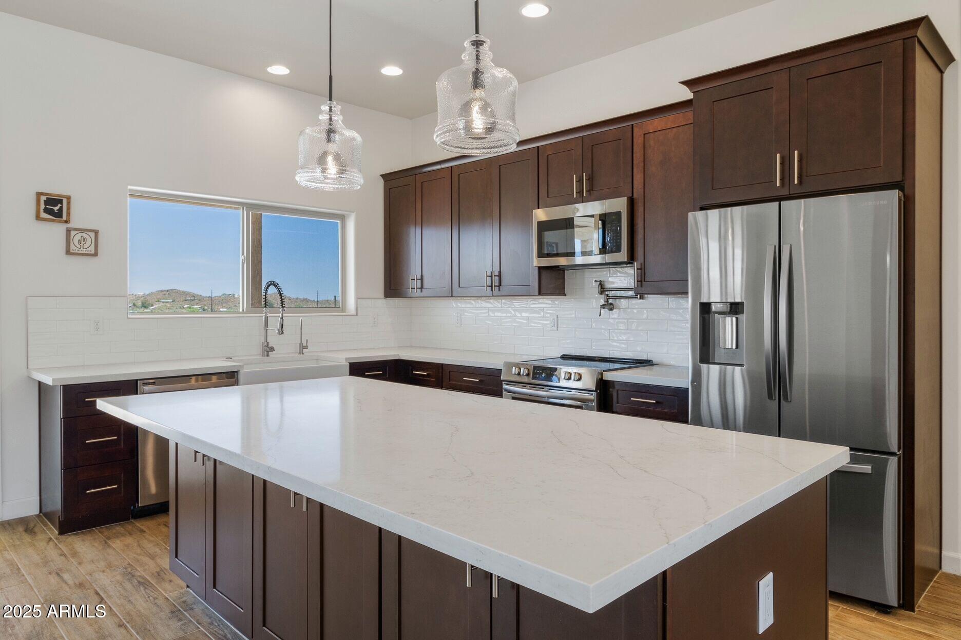 48126 North Coyote Pass Road New River, AZ 85087 - Photo 4 of 23 a kitchen with a refrigerator a sink a stove a microwave and island