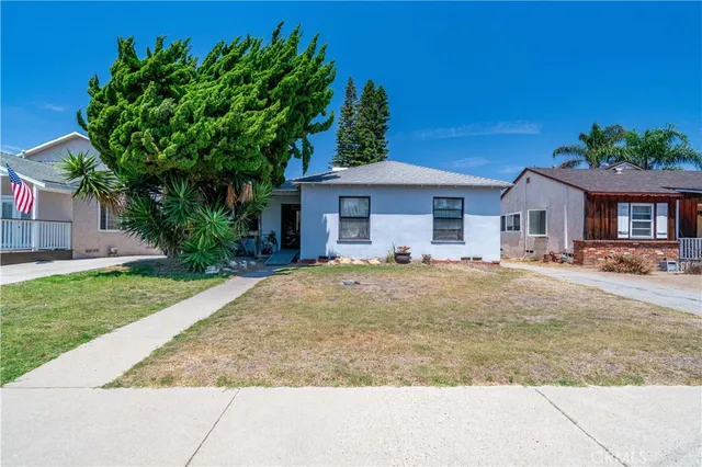 a view of a house with small yard plants and palm tree