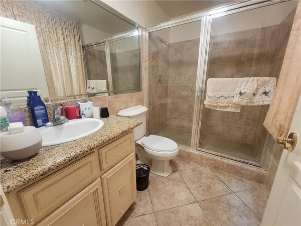 a bathroom with a granite countertop sink a toilet and shower
