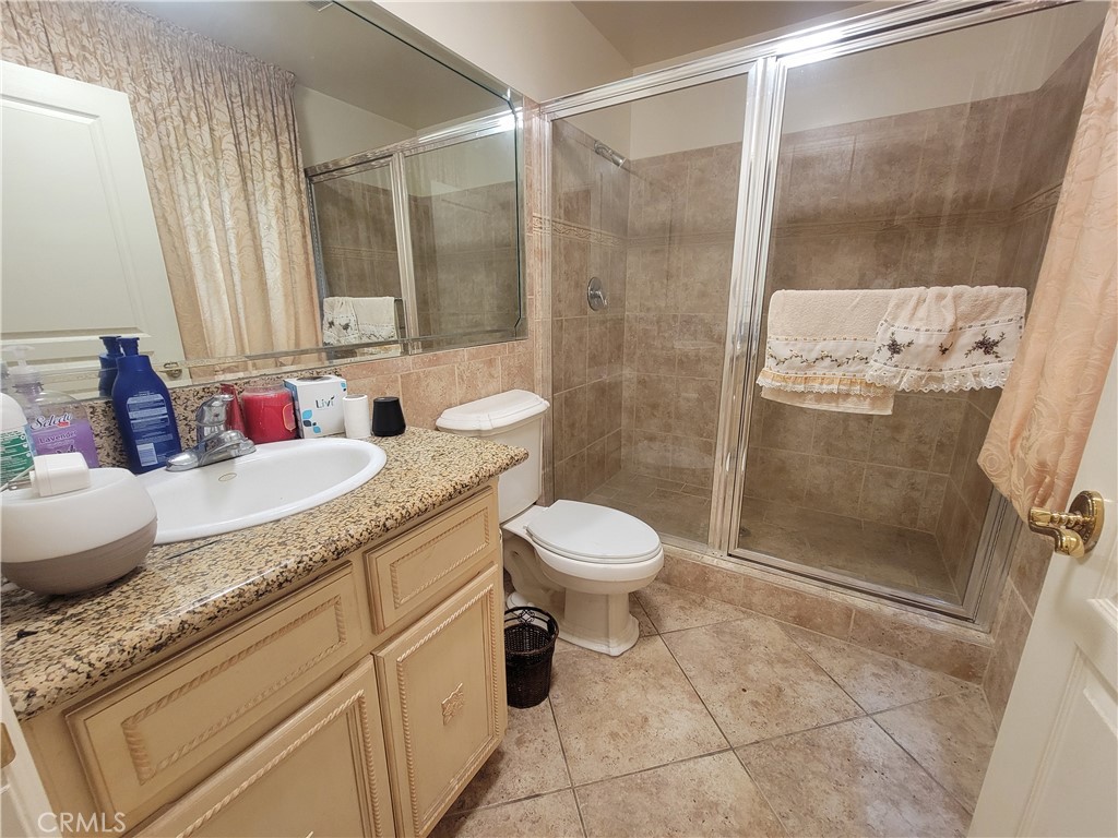 8009 Rose Street Paramount, CA 90723 - Photo 16 of 18 a bathroom with a granite countertop sink a toilet and shower