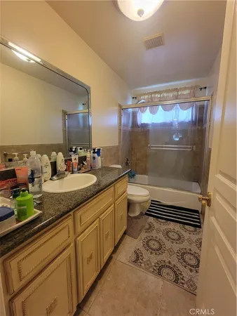 a bathroom with a granite countertop sink a toilet a mirror and shower