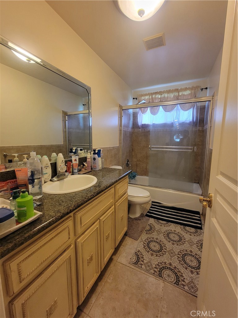 8009 Rose Street Paramount, CA 90723 - Photo 4 of 18 a bathroom with a granite countertop sink a toilet a mirror and shower