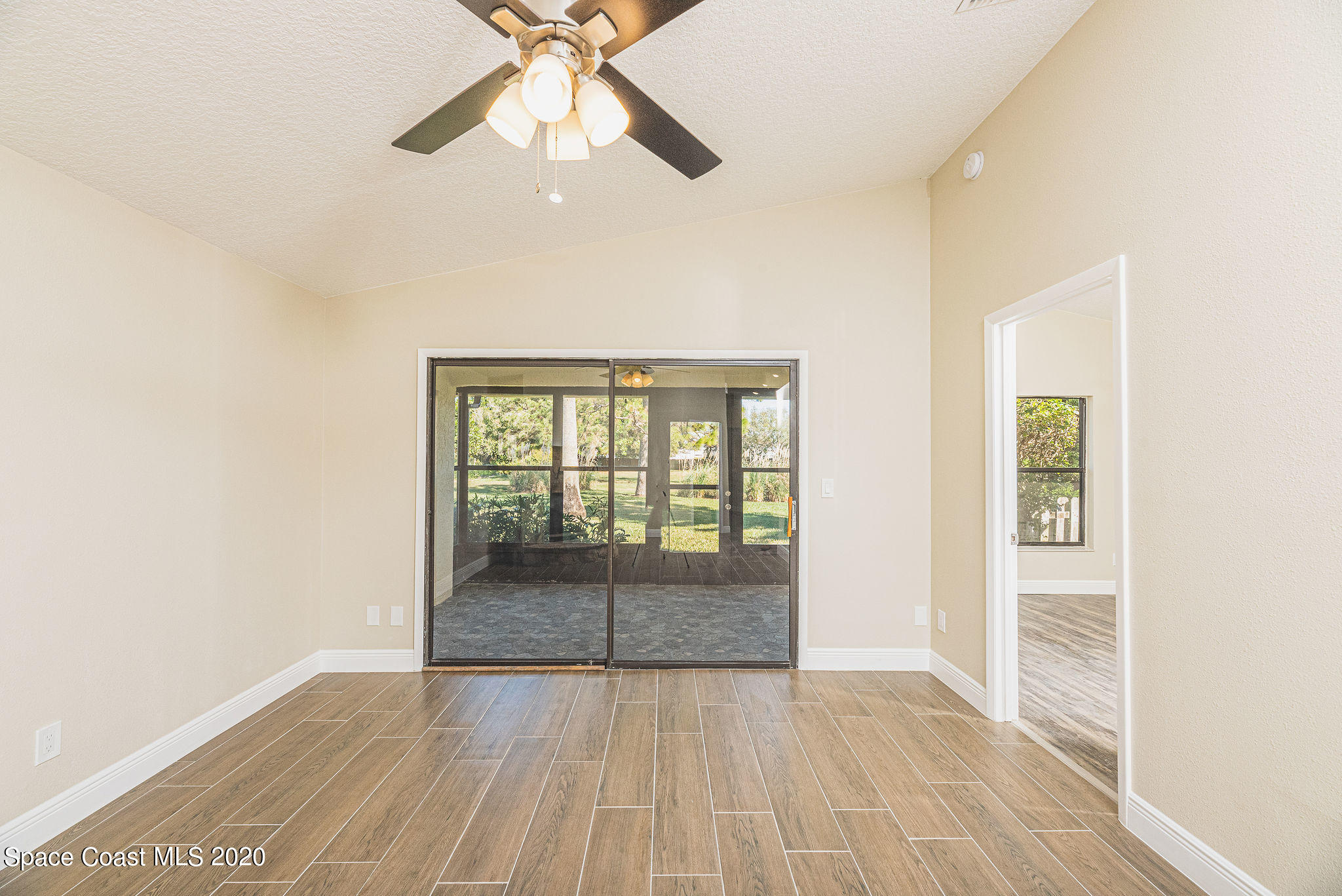 336 Myrtlewood Road Melbourne, FL 32940 - Photo 11 of 72 an empty room with wooden floor fan and windows
