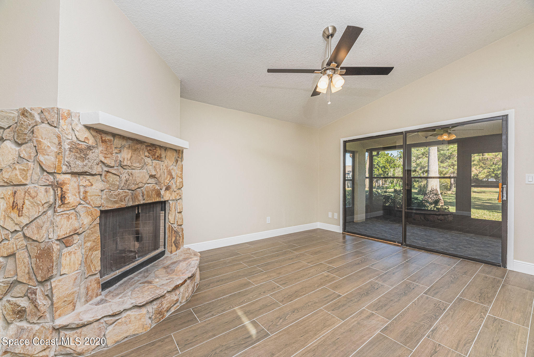 336 Myrtlewood Road Melbourne, FL 32940 - Photo 9 of 72 a view of an empty room with wooden floor and a fireplace